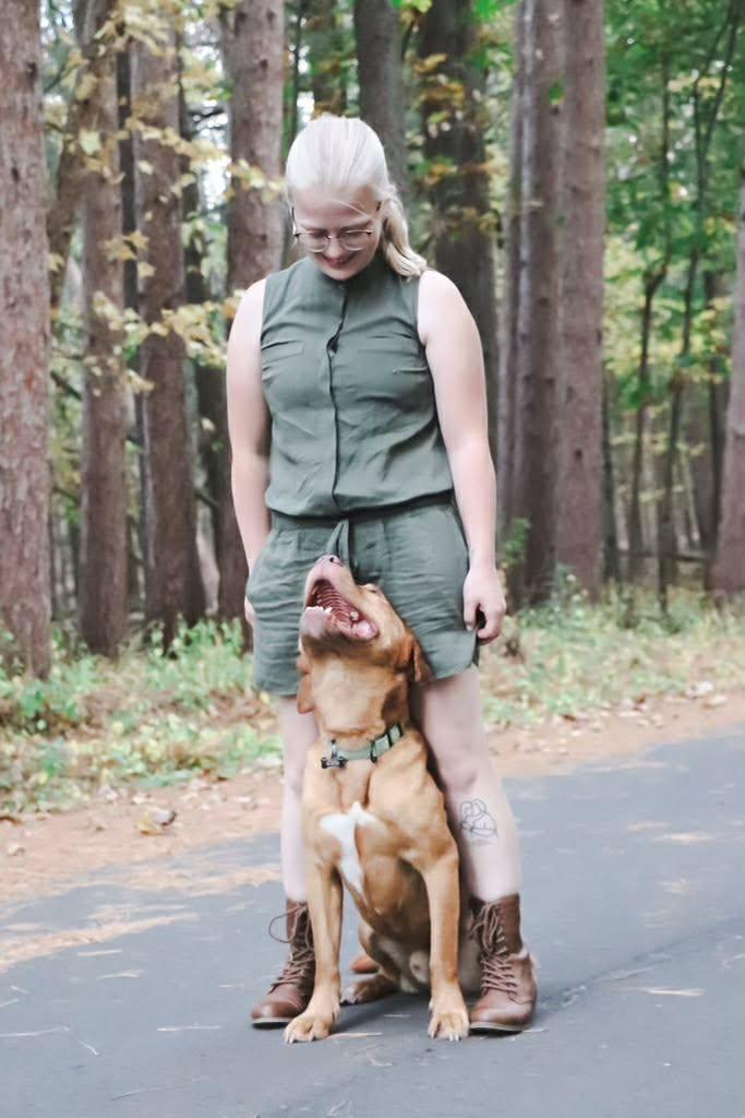 A red dog gazing up affectionately at Savannah on a forest path