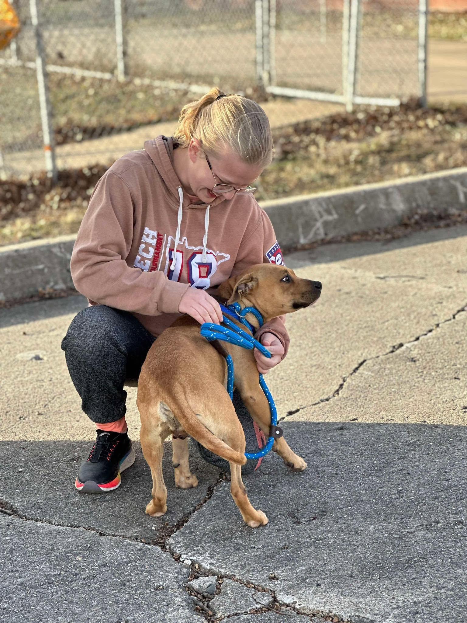 Savannah gently handling a small brown rescue puppy on a leash